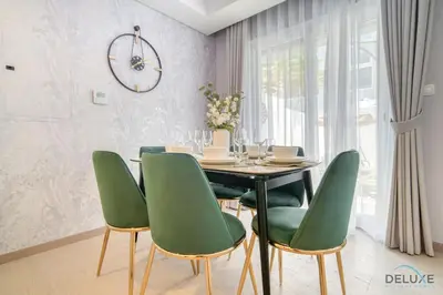 a dining room with a table and green chairs at Magnificent 3BR Townhouse at DAMAC Hills 2, Dubailand by Deluxe Holiday Homes in Dubai