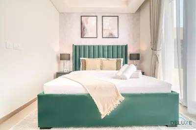 a bedroom with a large bed with a green headboard at Magnificent 3BR Townhouse at DAMAC Hills 2, Dubailand by Deluxe Holiday Homes in Dubai