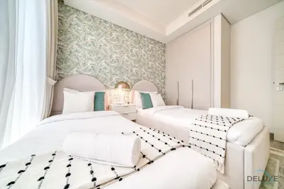 two beds in a room with white furniture at Magnificent 3BR Townhouse at DAMAC Hills 2, Dubailand by Deluxe Holiday Homes in Dubai