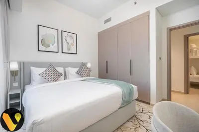 a white bedroom with a large bed and a chair at Vogue Downtown Act Two near Burj Khalifa and Dubai Mall, Three Bedroom Plus Kids room Apartment with Balcony and Burj Khalifa View, Access to all Amenities in Dubai