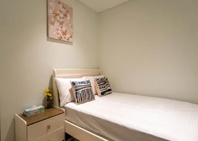 a small bedroom with a bed with white sheets and pillows at INA Homes - Act 1 Full Burj Khalifa and Fountain Views in Dubai