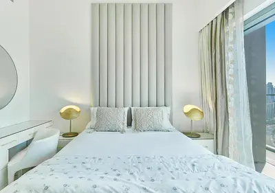 a white bedroom with a large bed and a window at FIRST CLASS 2BD, Full Burj Khalifa view in the Heart of Downtown in Dubai
