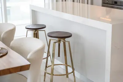 a kitchen with two bar stools next to a counter at Elegant seaside living 3-bedroom Emaar Beachfront by Suiteable in Dubai