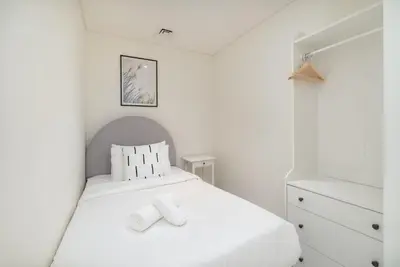 a white bedroom with a white bed and a dresser at Elegant seaside living 3-bedroom Emaar Beachfront by Suiteable in Dubai