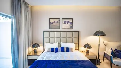a bedroom with a bed with blue sheets and two lamps at Luxurious Studio in Business Bay by Tanami Holiday Homes in Dubai