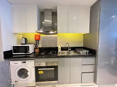 a kitchen with white cabinets and a washer and sink at Business Bay Modern studio with a Canal view at DAMAC Maison Prive 1616 in Dubai