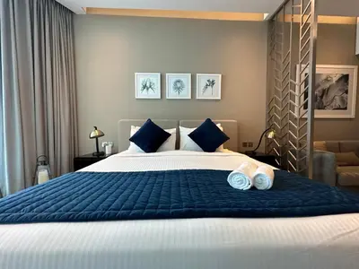 a bedroom with a large bed with blue sheets and blue pillows at Business Bay Modern studio with a Canal view at DAMAC Maison Prive 1616 in Dubai