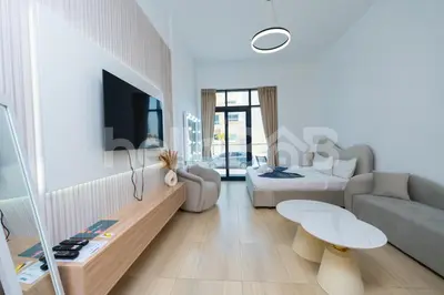 a white living room with a couch and a table at Le Petit Village !Cozy Yet Spacious Studio Apartment! in Dubai