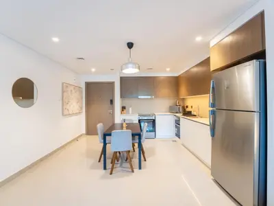 a kitchen with a table and chairs and a refrigerator at EasyGo - Exceptional 2BDR- Large Terrace-Pool Access in Dubai