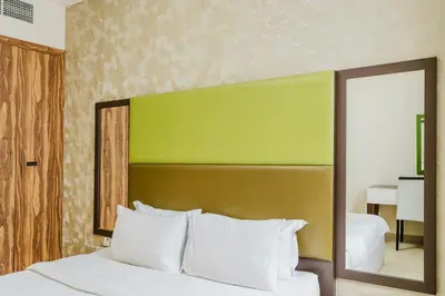 a bedroom with a bed with a green headboard and a mirror at RH - Spacious & Bright 01BR, Walk away to mall of Emirates in Dubai