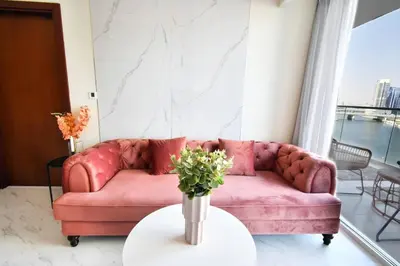a pink couch in a living room with a table at Reva tower- 2BR Dubai mall walking & canal facing in Dubai