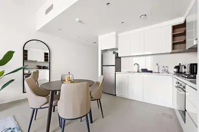 a kitchen with white cabinets and a table and chairs at Silkhaus chic 1BDR in the heart of Downtown in new tower in Dubai