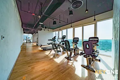 a row of treadmills in a gym with windows at Pristine Cozy One Bedroom Suite in Dubai