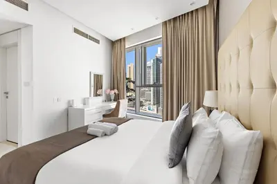 a bedroom with a large white bed with a large window at Chic 1BR Apt with Sofa Bed, Pool & Burj Khalifa View in Dubai