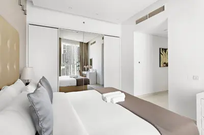 a bedroom with a white bed and a large mirror at Chic 1BR Apt with Sofa Bed, Pool & Burj Khalifa View in Dubai
