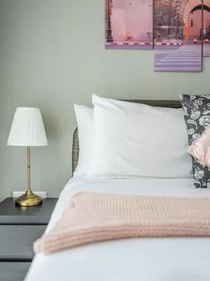 a bed with a pink blanket and a lamp on a table at Business Bay's Coziest Hideaway With Balcony in Dubai