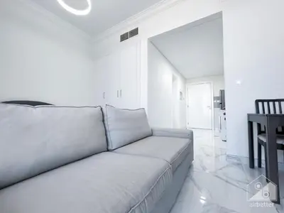 a white living room with a couch and a table at Spacious Studio with balcony in AL Majan in Dubai