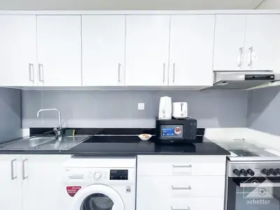a kitchen with a sink and a washing machine at Spacious Studio with balcony in AL Majan in Dubai