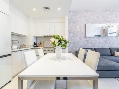 a white dining room table with a vase of flowers at Dazzling 1BR in Park Point - Dubai Hills in Dubai