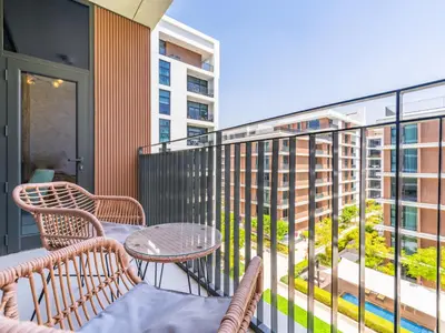 a balcony with two chairs and a table on a building at Dazzling 1BR in Park Point - Dubai Hills in Dubai