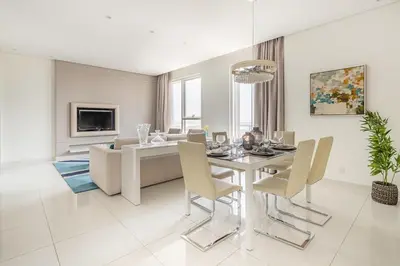 a white dining room with a table and chairs at Frank Porter - Damac Voleo in Dubai
