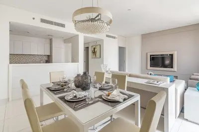 a white dining room with a table and chairs at Frank Porter - Damac Voleo in Dubai
