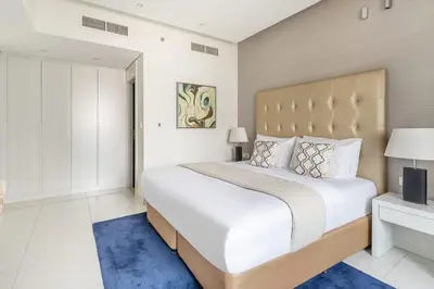 a bedroom with a large white bed with a large headboard at Frank Porter - Damac Voleo in Dubai