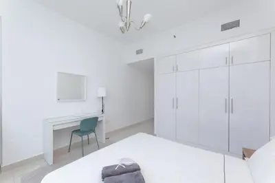 a white bedroom with a bed and a desk at Waterfront With Stunning View! in Dubai