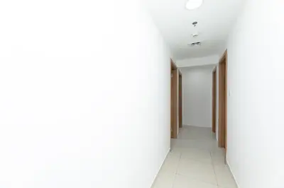 an empty corridor with white walls and white tile floors at Waterfront With Stunning View! in Dubai