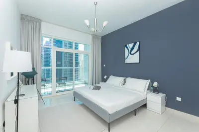 a blue bedroom with a bed and a window at Waterfront With Stunning View! in Dubai
