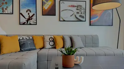 a living room with a gray couch and pictures on the wall at Paramount Tower Hotel and Residences with Infinity Sky Pool in Dubai
