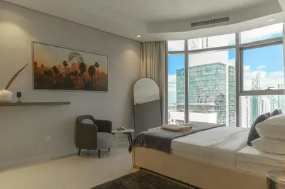a bedroom with a bed and a chair and a window at Paramount Tower Hotel and Residences with Infinity Sky Pool in Dubai