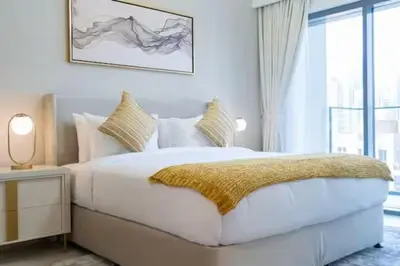 a white bedroom with a large bed and a window at Vogue Downtown Burj Royale near Dubai Mall and Burj Khalifa ,Two Bedroom Apartment with large Balcony and Access to all Amenities in Dubai