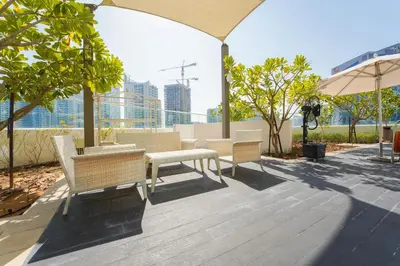 a patio with chairs and tables and an umbrella at ALiving Classy Private Studio I Canal Views I DAMAC Maison Prive A- 2111 in Dubai
