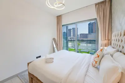 a bedroom with a white bed and a large window at EasyGo - Sobha Waves 1 Bedroom & Study Modern in Dubai