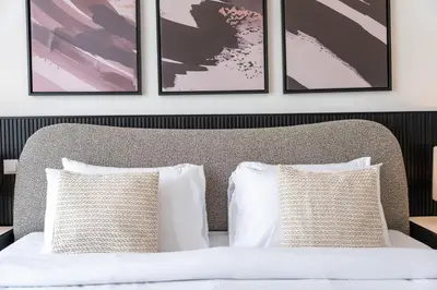a bedroom with a bed with four framed pictures on the wall at Executive Studio in Damac Hills by Suiteable in Dubai