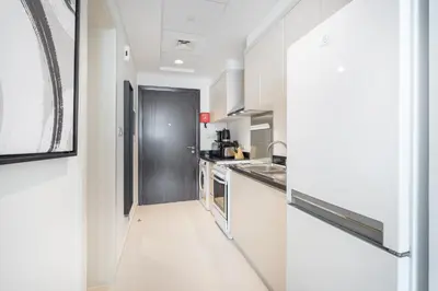 a kitchen with white walls and a long hallway at Executive Studio in Damac Hills by Suiteable in Dubai