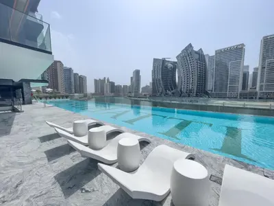 a row of white lounge chairs next to a swimming pool at Canal front apartment with Burj Khalifa view by Suiteable in Dubai