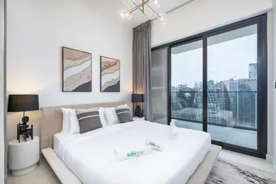 a bedroom with a large white bed with a large window at Canal front apartment with Burj Khalifa view by Suiteable in Dubai