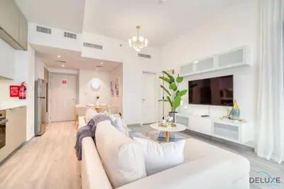 a living room with a white couch and a kitchen at Polished 1BR at Noor 1 Midtown Dubai Production City by Deluxe Holiday Homes in Dubai