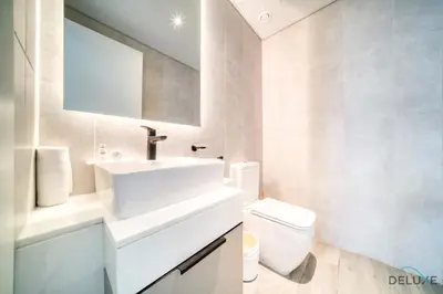 a white bathroom with a sink and a toilet at Polished 1BR at Noor 1 Midtown Dubai Production City by Deluxe Holiday Homes in Dubai