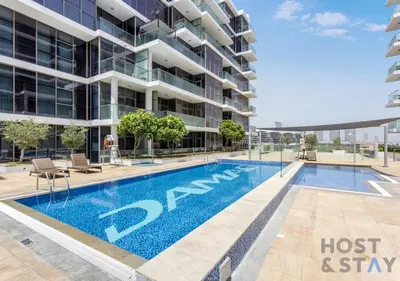 a swimming pool in front of a building at Studio in Jasmine, Damac Hills - Host & Stay in Dubai