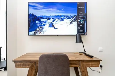 a tv screen hanging on a wall with a desk at Special Rates - Elegant Studio - Golf Views in Dubai