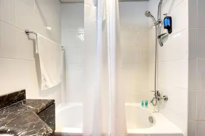 a white bathroom with a shower and a sink at RH- Studio Retreat, Walk away to Burj Khalifa and Dubai Mall in Dubai