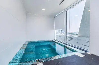 a swimming pool in a bathroom with a window at Waves Holiday Homes - Chic Studio With Balcony Overlooking City Views in Dubai