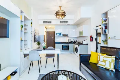 a living room and kitchen with a table and a couch at Waves Holiday Homes - Chic Studio With Balcony Overlooking City Views in Dubai