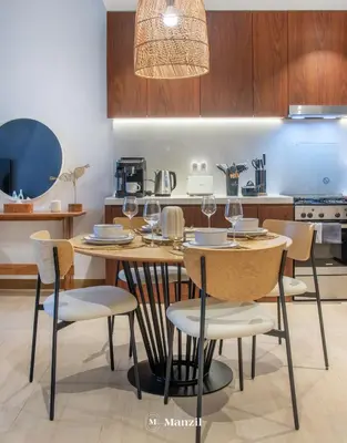 a kitchen with a wooden table with chairs and a dining room at Manzil - 1BR Home in Port de la Mer w Lake Access in Dubai