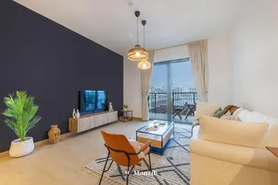 a living room with a couch and a tv at Manzil - 1BR Home in Port de la Mer w Lake Access in Dubai