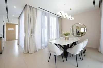a dining room with a table and chairs and a mirror at NewArabian Dubai Hills Sidra Villa in Dubai