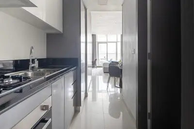 a white kitchen with a sink and a table at Frank Porter - Prive A in Dubai